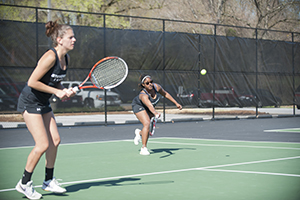 Freshman Christina Endy gets ready, while junior Ty-Chelle Williams stretches for a forehand during the Mustang's home match against Hood College