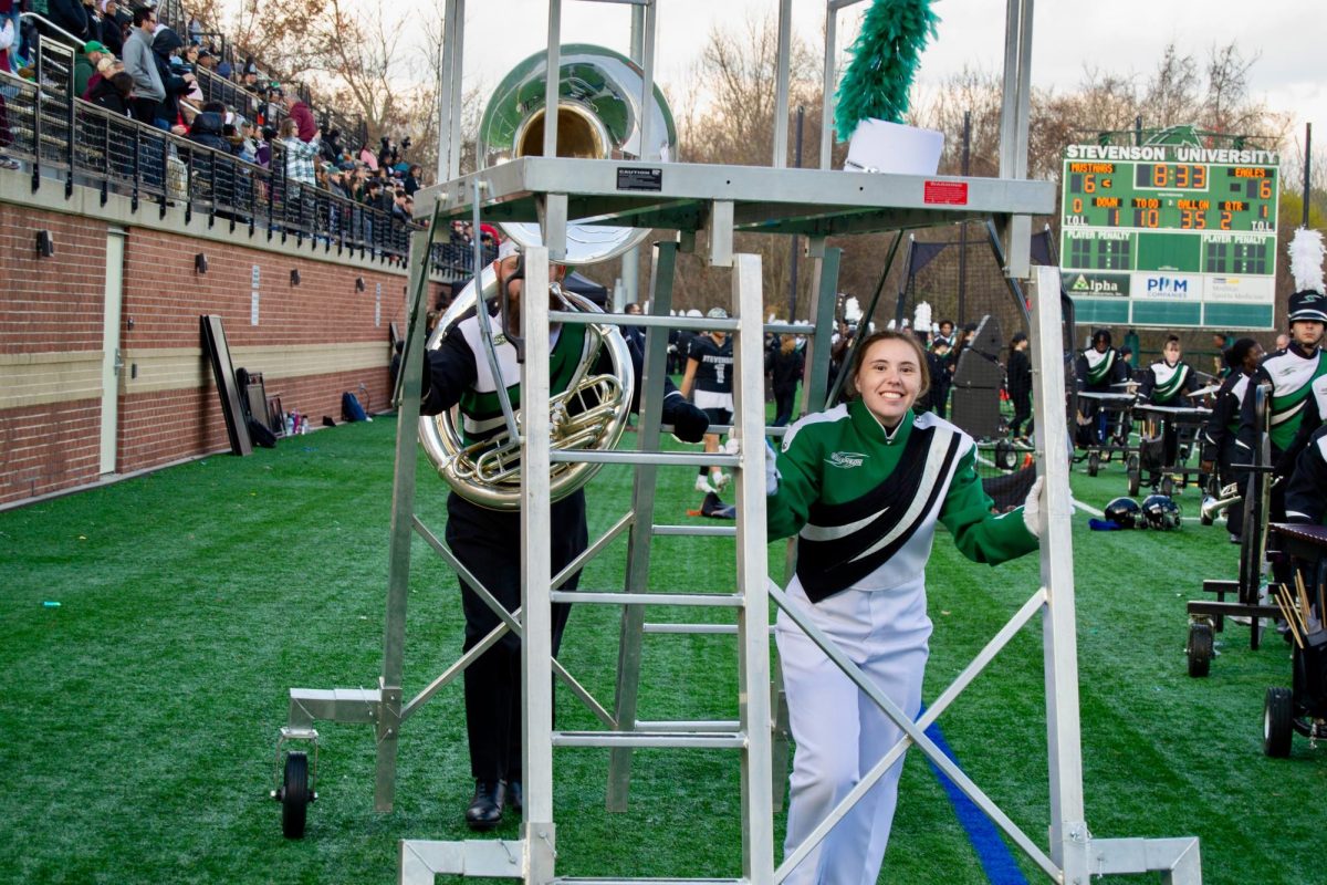 Emily Fox stands under the platform shell climb so that she can direct Stevensons marching band at a football halftime show.