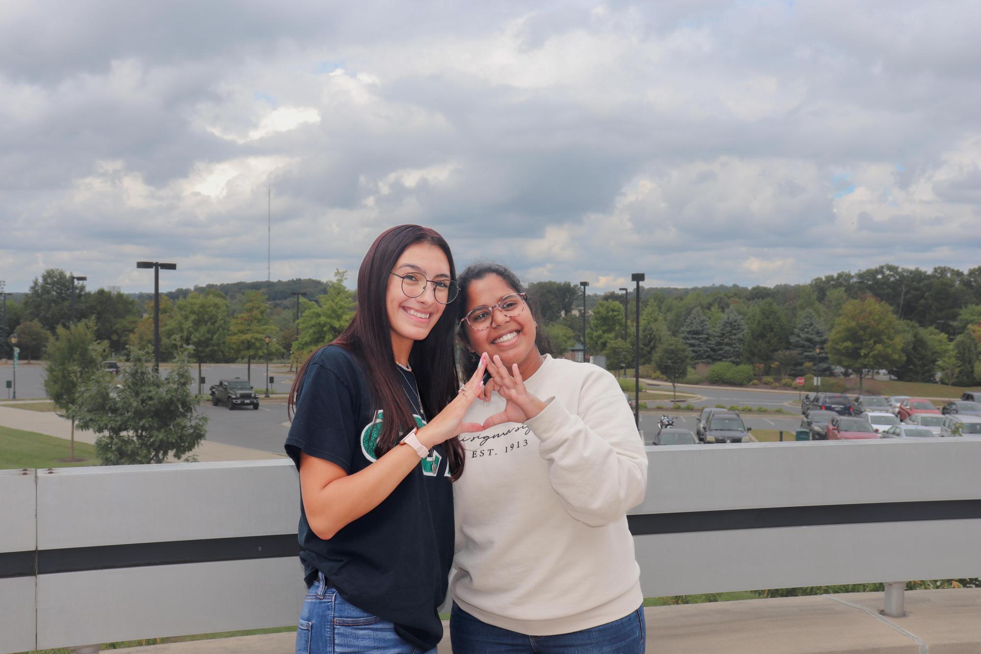 Julia Barreda and Kera Skove form the Phi Sigma Sigma hand-sign at a recruitment retreat.