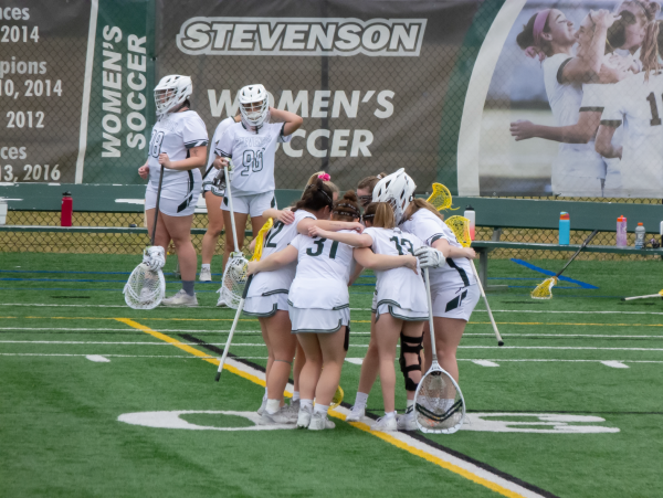 Womens lacrosse huddles together for a play 