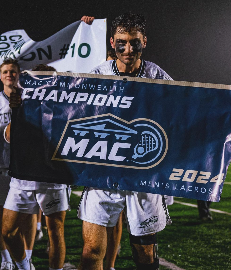 Senior midfielder Andrew Searing holds the MAC championship banner after the Mustangs defeated Eastern 21-3 in the MAC title game Saturday at Mustang Stadium.