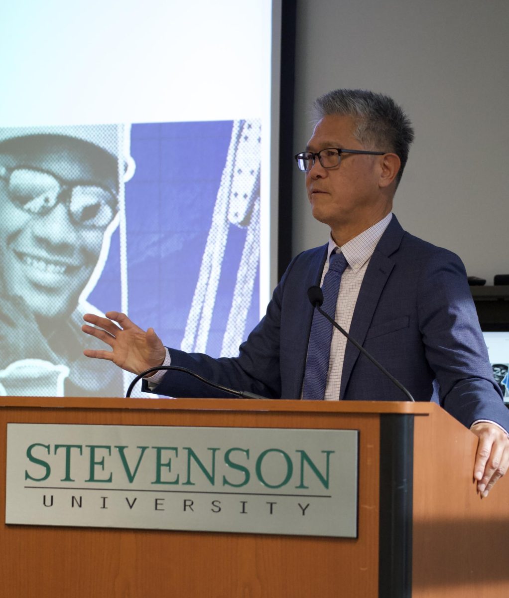 Baltimore Banner reporter Hugo Kugiya speaks to a Stevenson University audience Thursday on the value of human creativity in the age of artificial intelligence during the 16th annual Shapiro-Rouse Lecture in Garrison Hall North's Claire Moore Room.