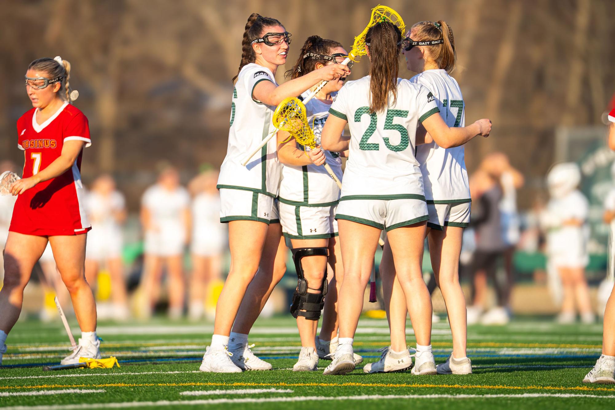 Women's lacrosse celebrates after scoring against Ursinus College