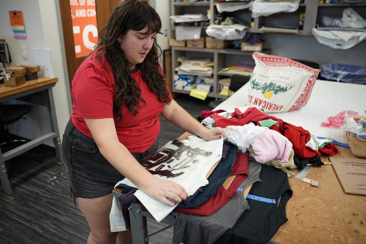 Martin sorts out a pile of thrifted clothing in order to begin the process of sizing the print for each shirt.