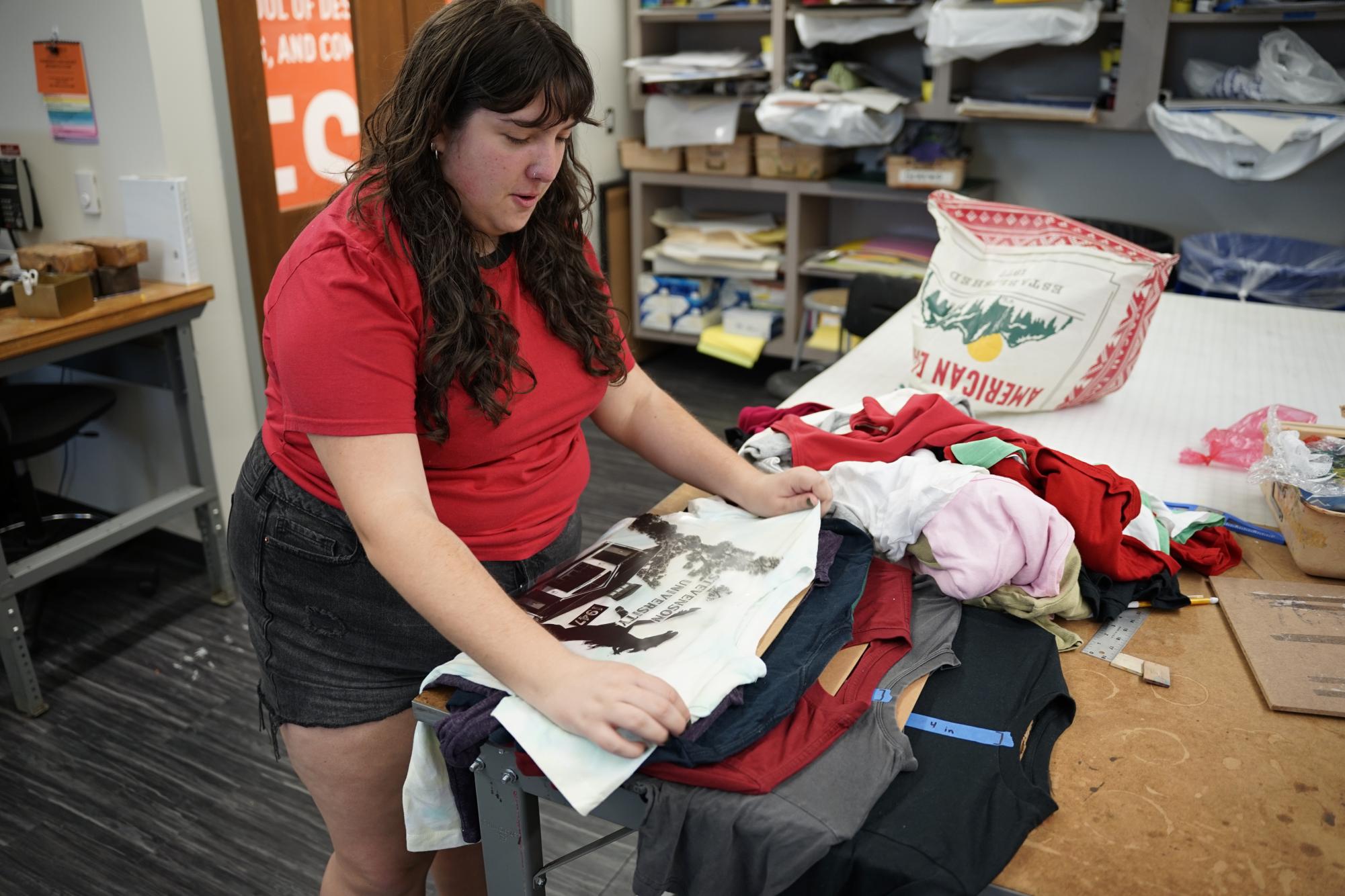 Martin sorts out a pile of thrifted clothing in order to begin the process of sizing the print for each shirt.